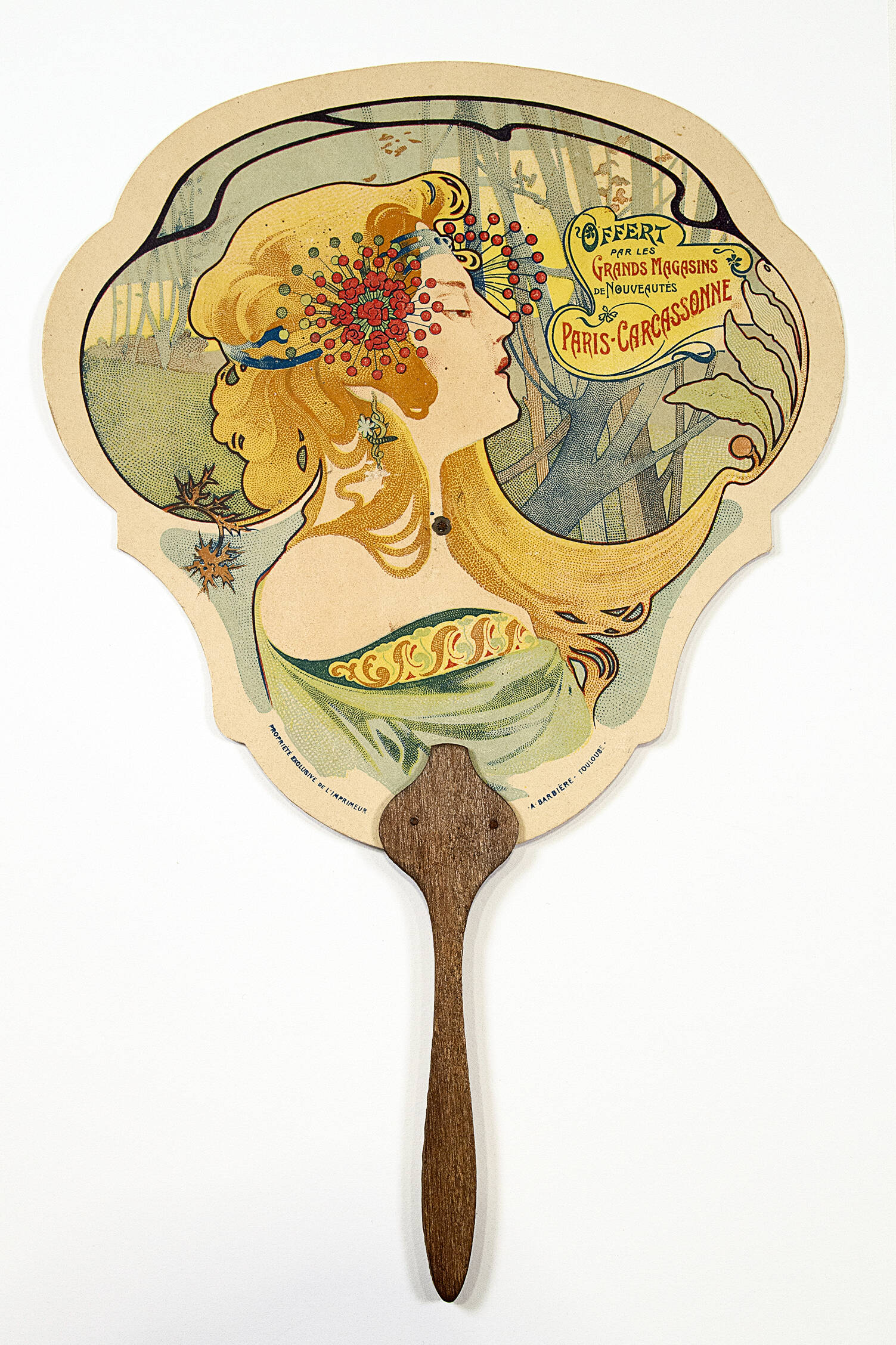 French print fan with wooden handle. Paper fan has a side profile of a woman with a delicate forest scene behind her.